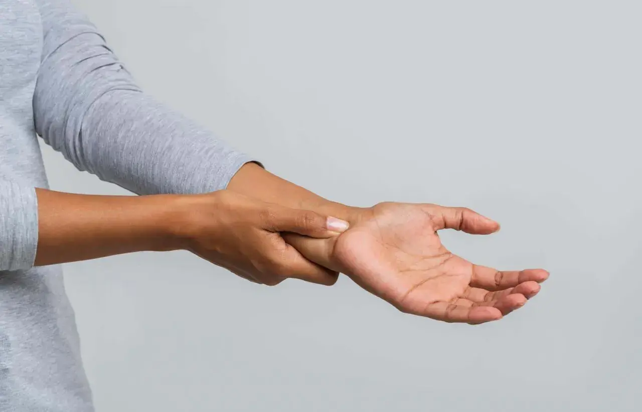 Eine Person hält sich das Handgelenk, als ob sie ein Ziehen im Handgelenk spürt.