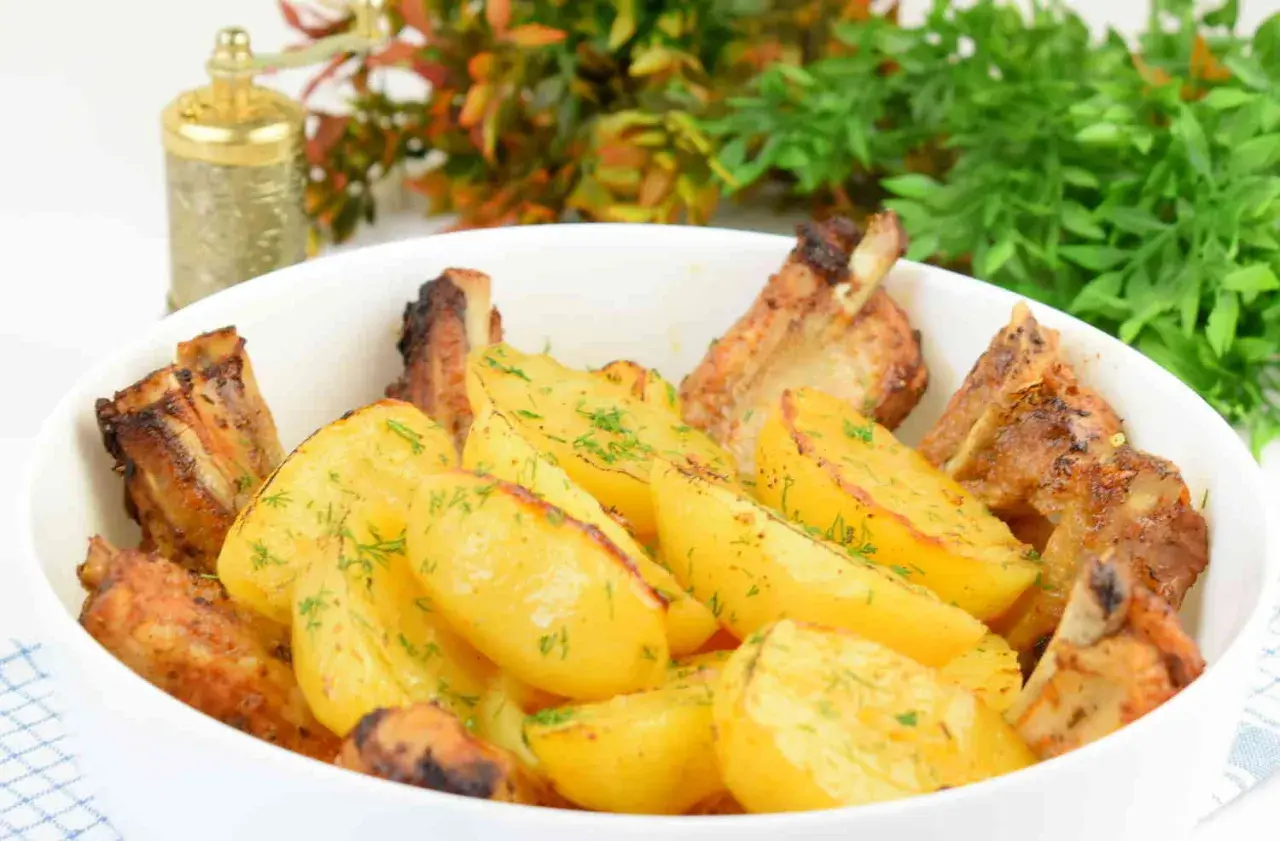 Soczyste żeberka pieczone z ziemniakami, posypane koperkiem. Idealny sposób, jak piec żeberka, by były pyszne.