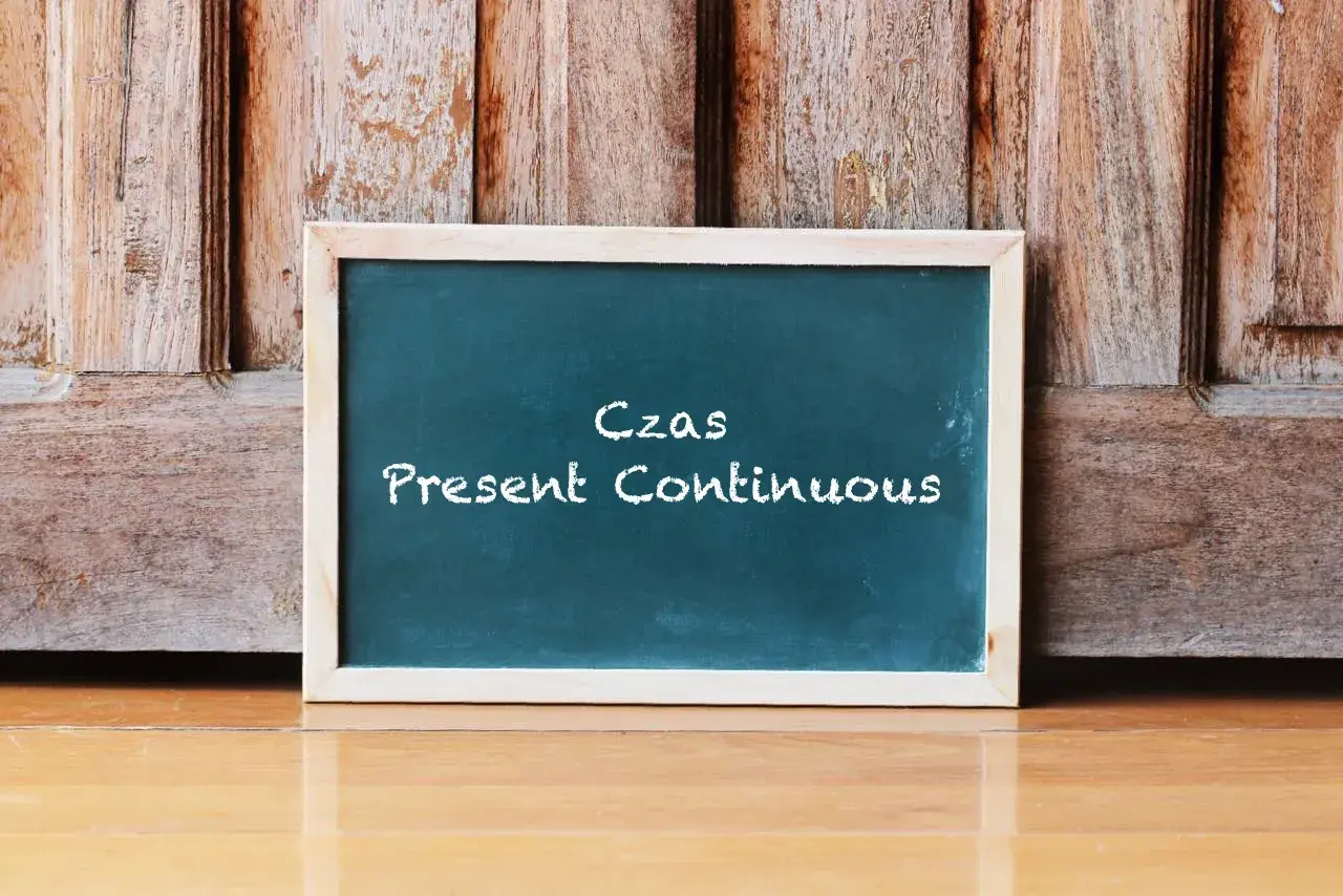 Tablica z napisem "Czas Present Continuous" na tle drewnianych drzwi. Uczysz się, co to jest present continuous?