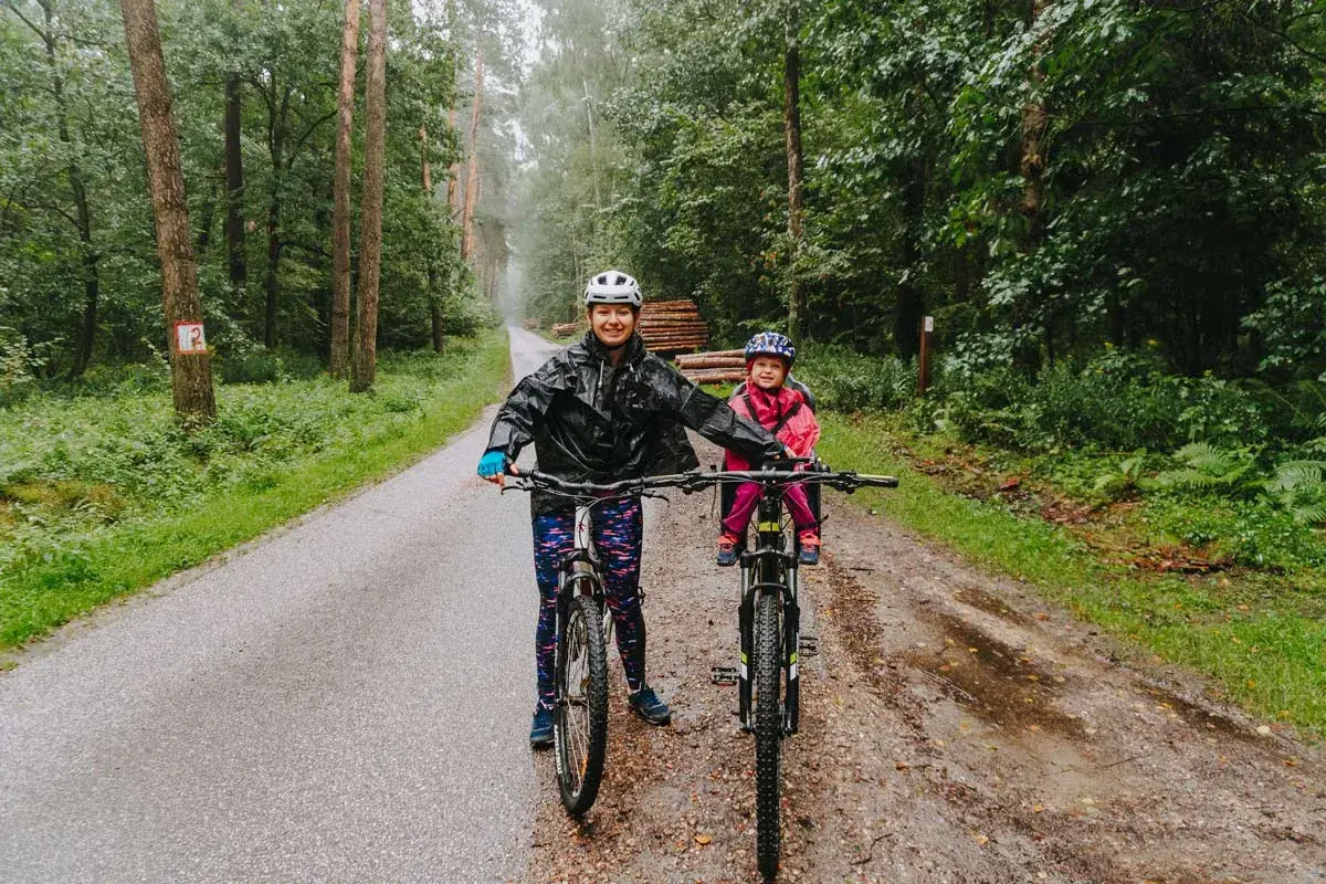 Mama i dziecko na rowerach w deszczu, odkrywają lasy kozłowieckie trasy rowerowe.