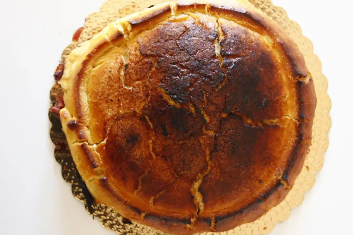 Crostata ricotta e visciole dorata, con la crosta leggermente bruciacchiata e un ripieno invitante.