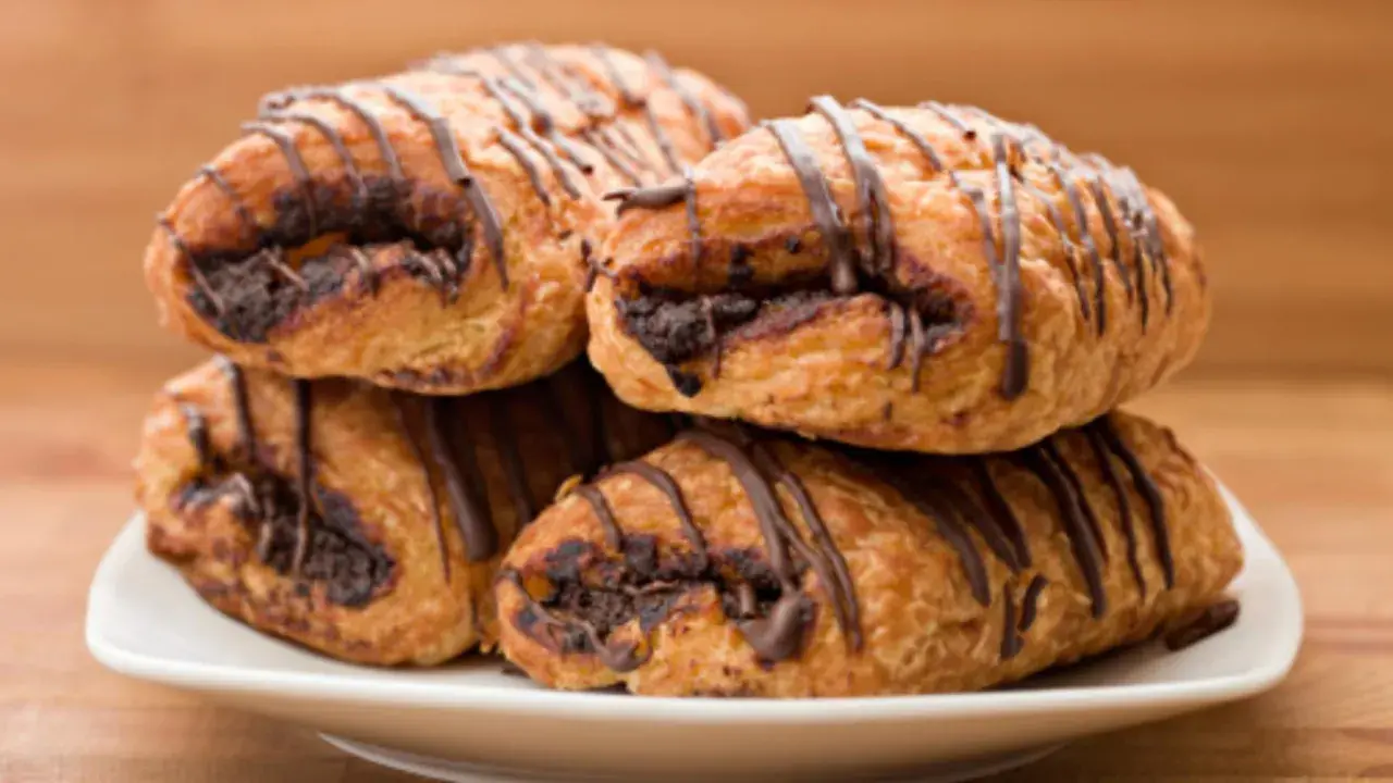 Cuatro napolitanas de chocolate apiladas en un plato blanco, con un glaseado de chocolate oscuro.