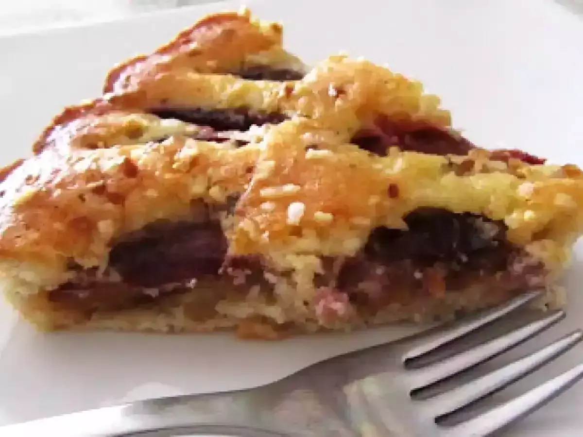 Una fetta di torta con prugne fresche, con crosta dorata e ripieno succoso, pronta per essere gustata.