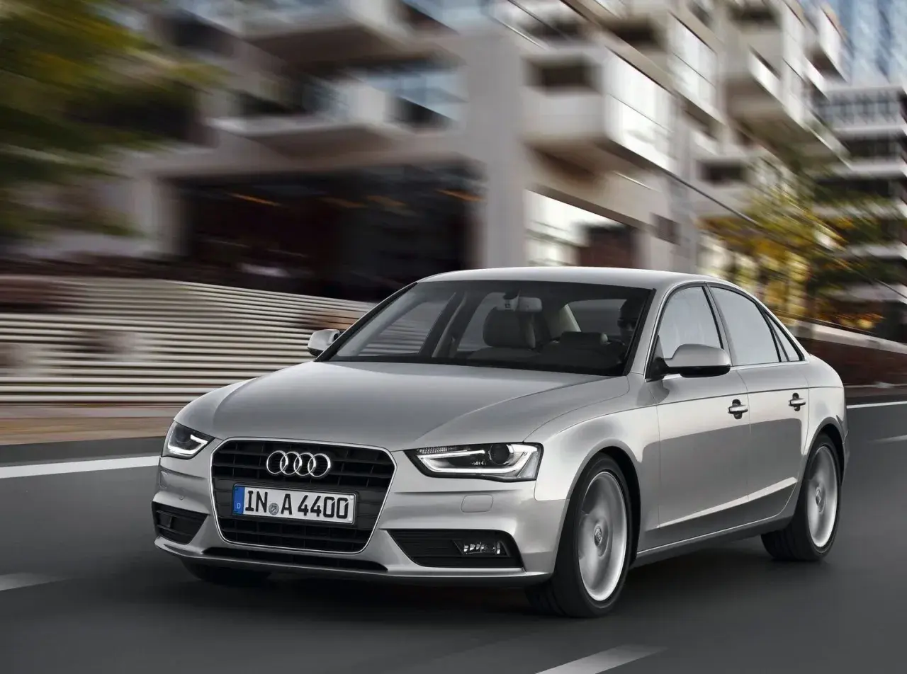 Srebrne Audi A4 B8 w ruchu miejskim. Typowe usterki tego modelu mogą dotyczyć elektroniki lub układu napędowego, ale ten egzemplarz wygląda bez zarzutu.