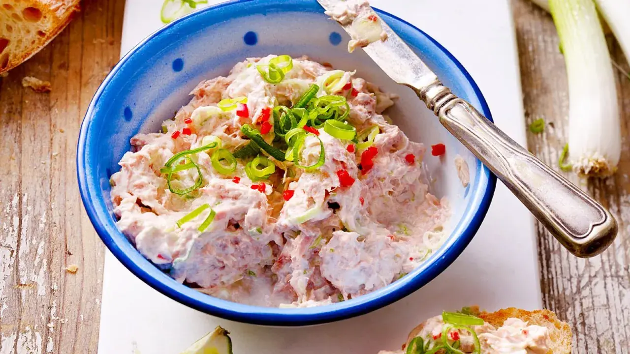 Cremiger Thunfisch-Dip mit Frühlingszwiebeln und Chili, garniert auf Brot.
