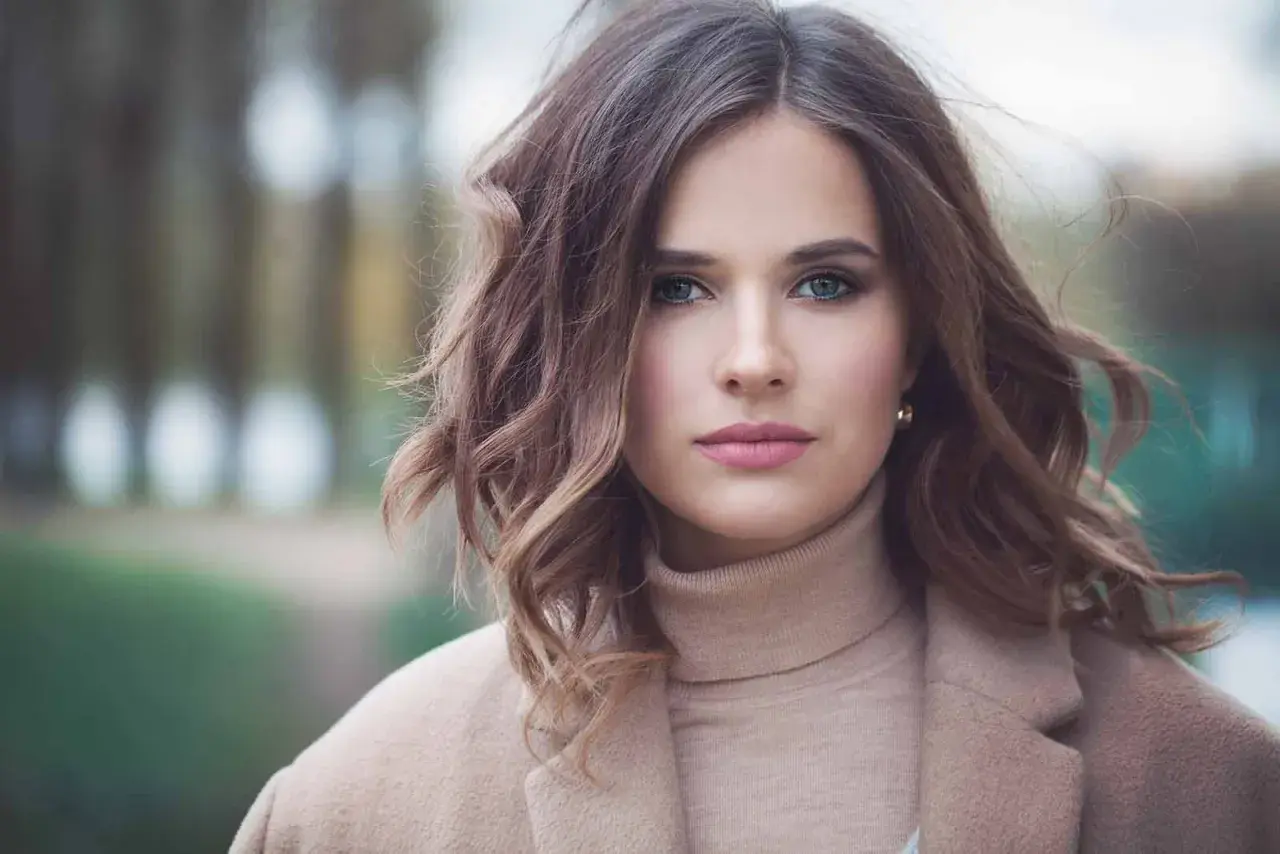 Mujer con peinados media melena modernos, ondas suaves y un abrigo beige.