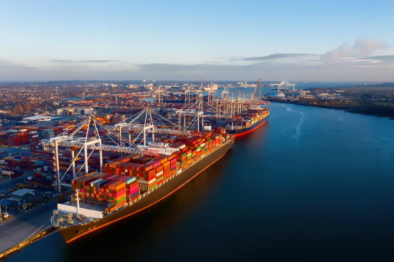 Großer Containerhafen mit Schiffen und Kränen. Die Einfuhr-Zollabfertigung ist hier ein wichtiger Prozess für den globalen Handel.