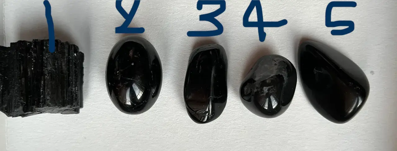 Pięć próbek czarnego minerału, od surowego kryształu po gładkie kamienie.