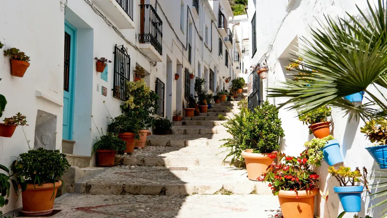 Calle empedrada con escaleras y casas blancas adornadas con macetas. Un ejemplo de los pueblos bonitos cerca de Vera.