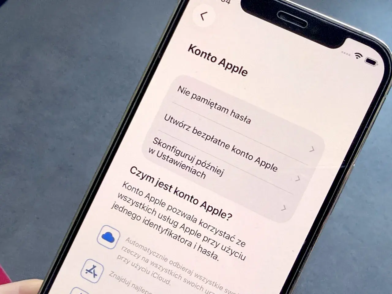 Ekran telefonu z opcjami konta Apple: "Nie pamiętam hasła", "Utwórz bezpłatne konto Apple", "Skonfiguruj później w Ustawieniach". Dowiedz się, jak wejść w ustawienia telefonu.