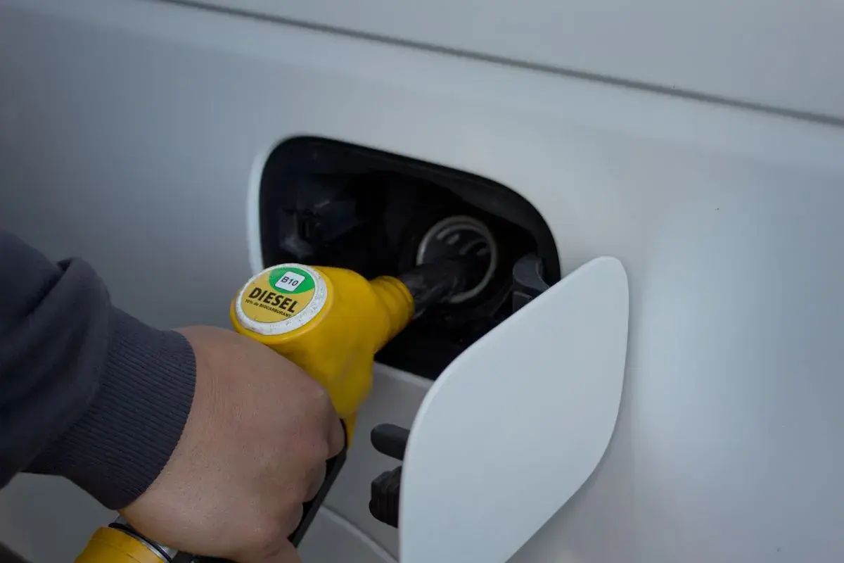 Ręka trzymająca żółtą dyszę dystrybutora z napisem DIESEL B10, tankująca samochód.