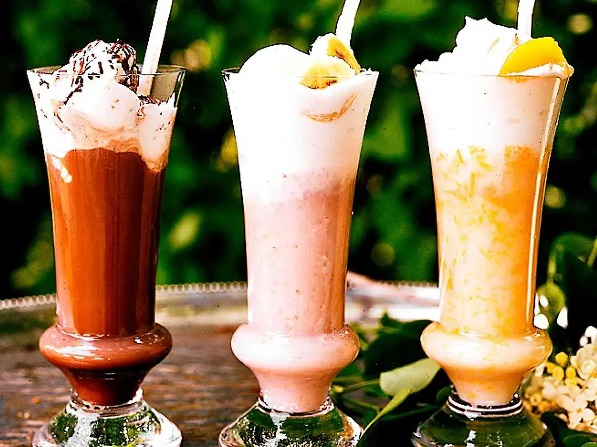 Tre läckra milkshakes i glas med grädde och strössel. Perfekt för ett somrigt milkshake recept!