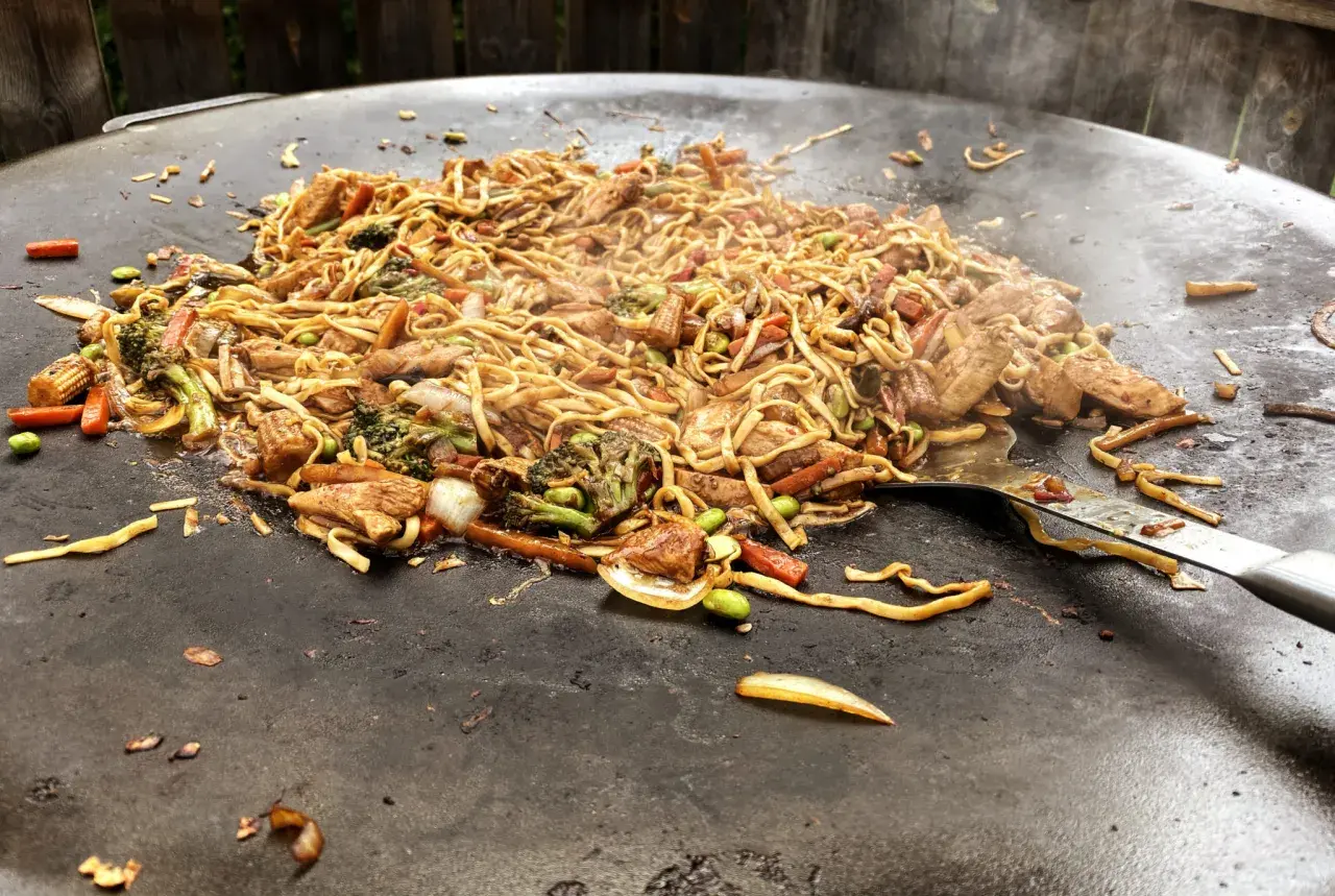 En wok med nudlar, kyckling och grönsaker tillagas på en muurikka. Ett perfekt recept för en muurikka wok!