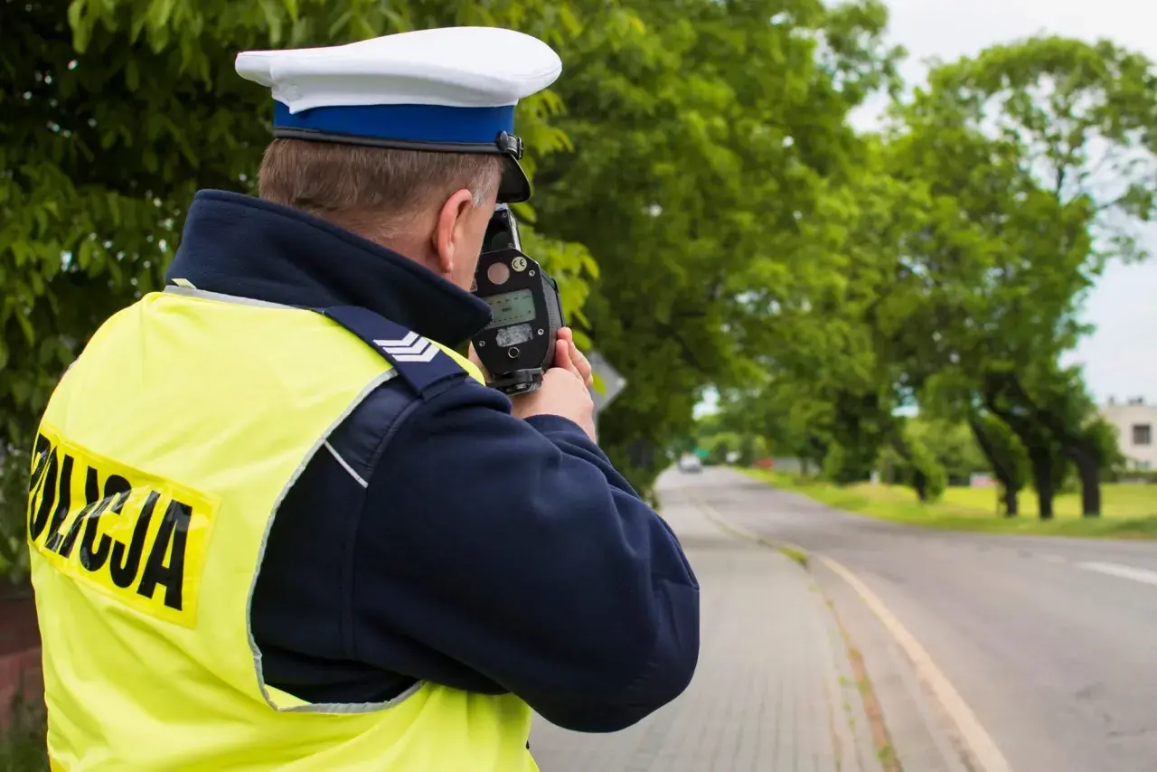 Policjant mierzy prędkość. Kierowco, uważaj na przekroczenie prędkości o 20 w terenie zabudowanym, bo możesz dostać mandat.