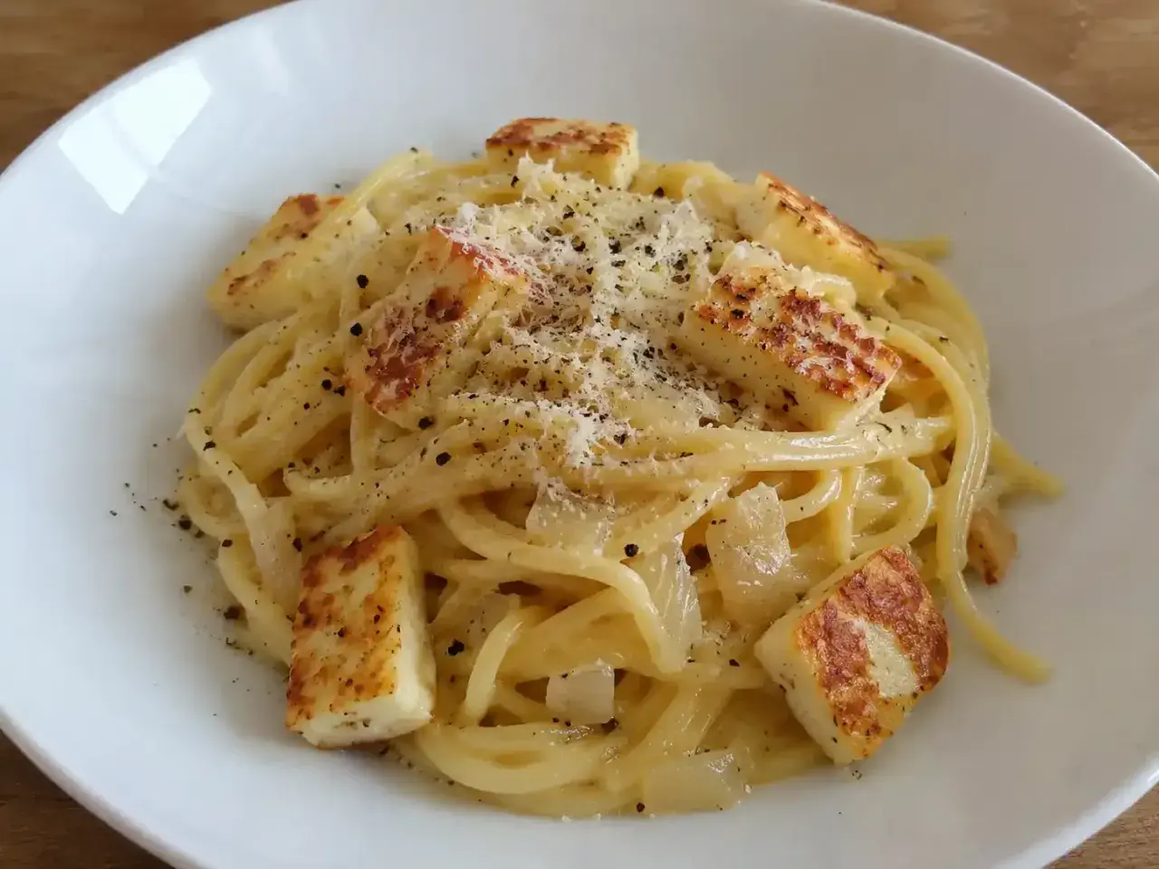 En krämig vegetarisk carbonara med spaghetti, stekt halloumi och rikligt med parmesanost och svartpeppar.