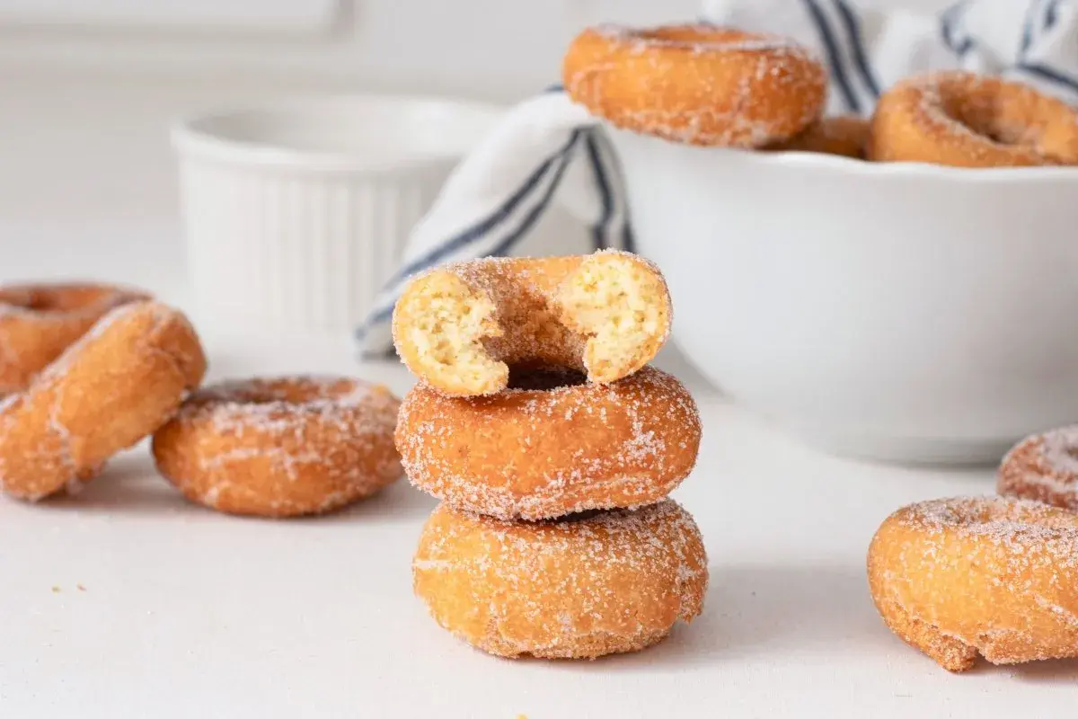 Rosquillas caseras de toda la vida, doradas y espolvoreadas con azúcar, apiladas y esparcidas. Un placer que evoca recuerdos.