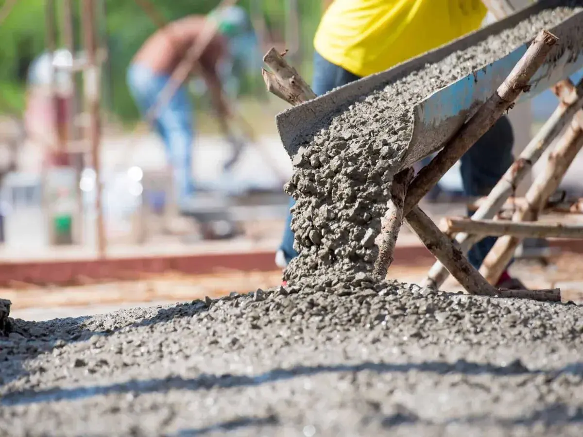 Beton wylewany z rynny na placu budowy. Kluczowe dla prawidłowego wykonania prac jest to, jak obliczyć ilość betonu na wylewkę.