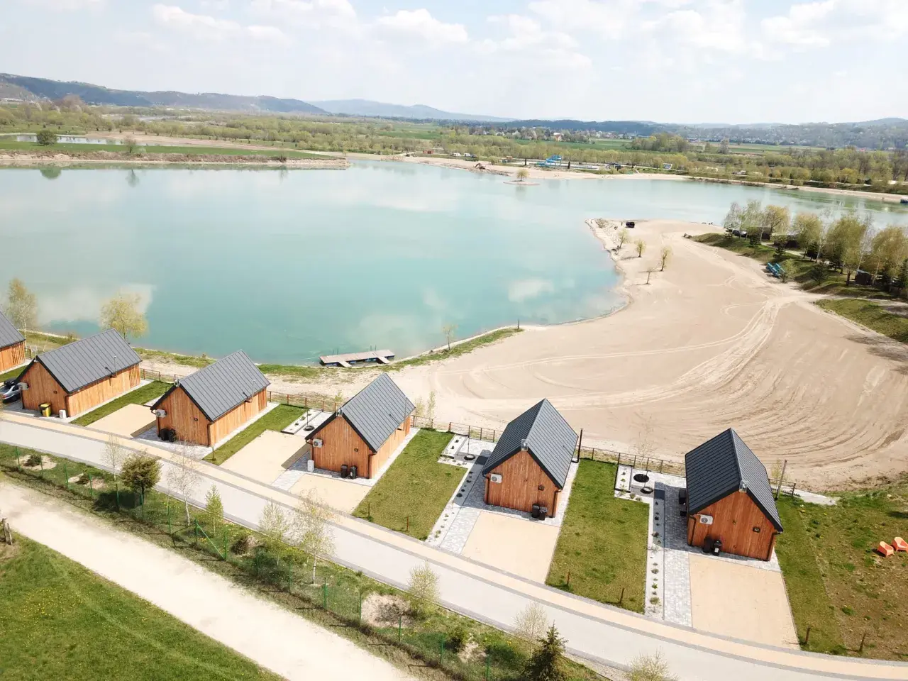 Drewniane domki nad turkusową wodą, idealne na wypoczynek w stylu kąpielisko Mała Chorwacja. Piękny piasek i zieleń wokół.