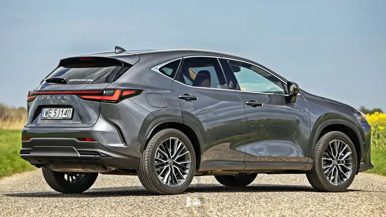 Szary Lexus NX 450h+ na drodze, obok pola rzepaku. Sprawdź aktualną lexus nx cena.