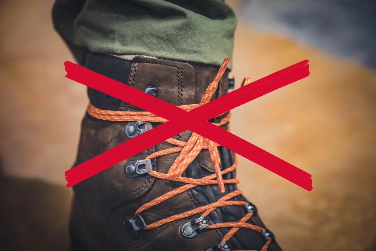 A red X crosses over a brown hiking boot with orange laces. The question "why are boot laces so long?" is implied.