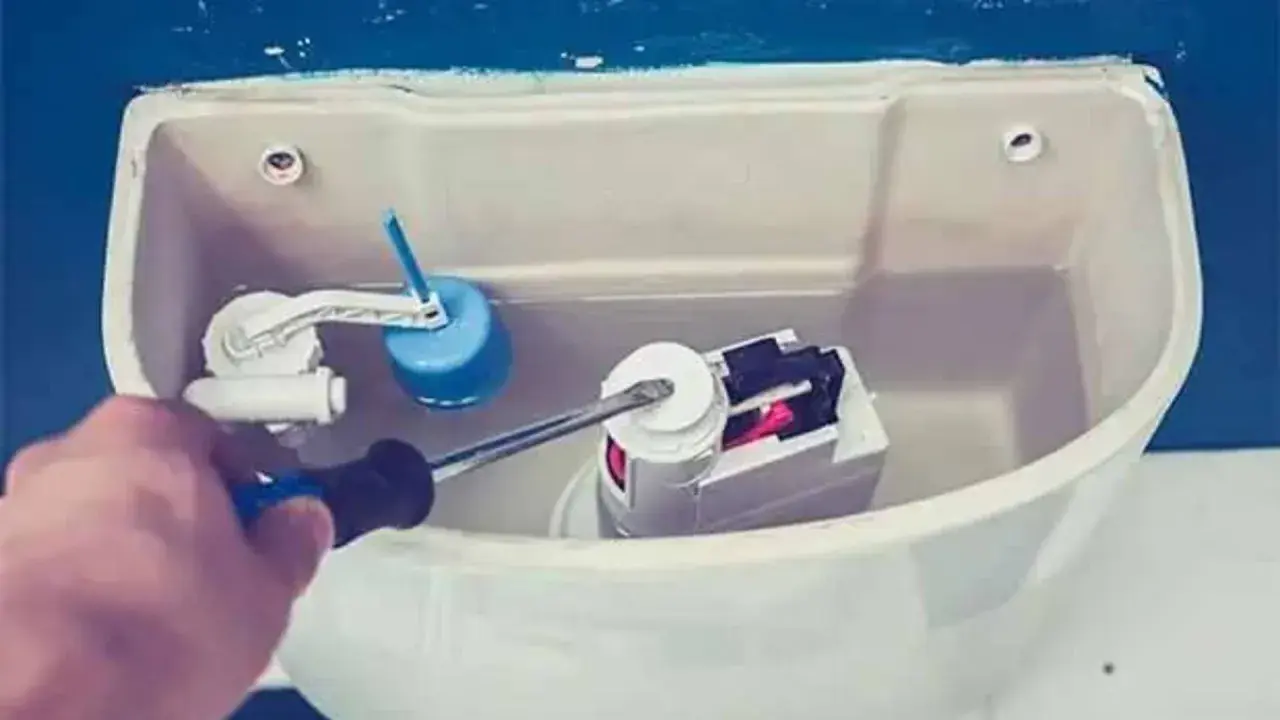 Mano con cacciavite che regola il meccanismo interno di uno scarico del water.