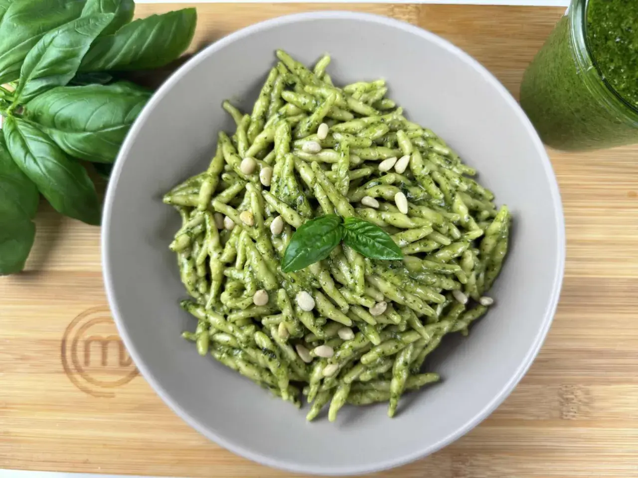 Piatto di trofie al pesto, guarnite con pinoli e basilico fresco. Un classico delle trofie ricette, pronto da gustare.