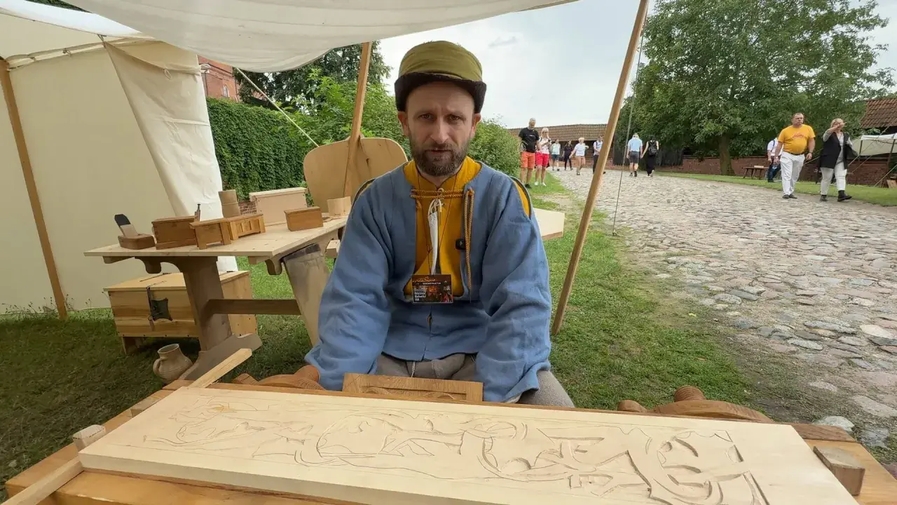 Snycerz co robi? Rzeźbi w drewnie, tworząc misterny wzór na desce.