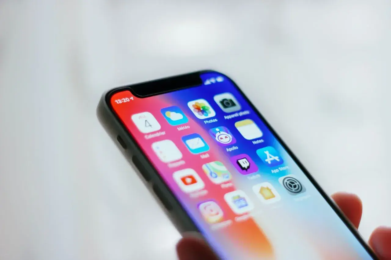 Zbliżenie na ekran smartfona z widocznymi ikonami przydatnych aplikacji, takich jak Kalendarz, Pogoda, Zdjęcia, Notatki i App Store.