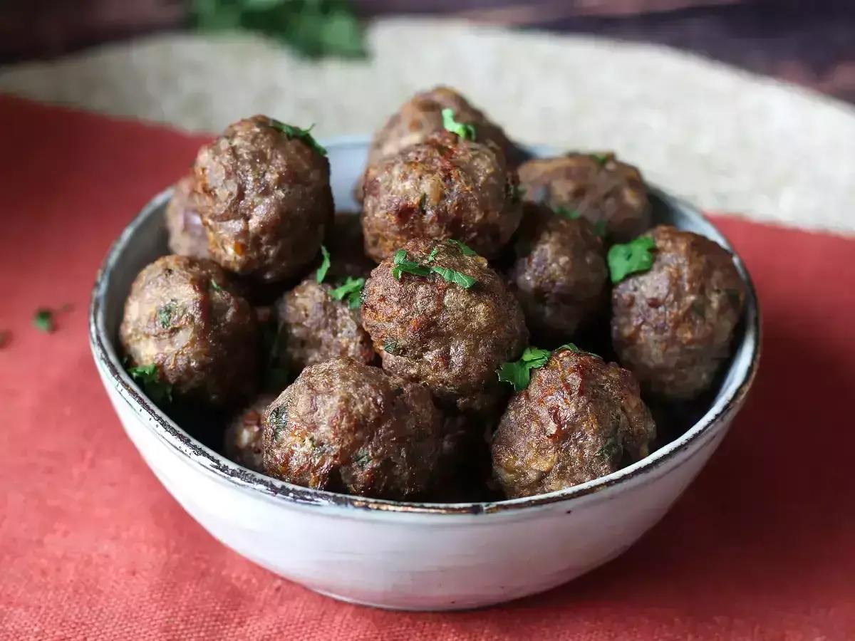 Succulente polpette in friggitrice ad aria, dorate e profumate, guarnite con prezzemolo fresco.