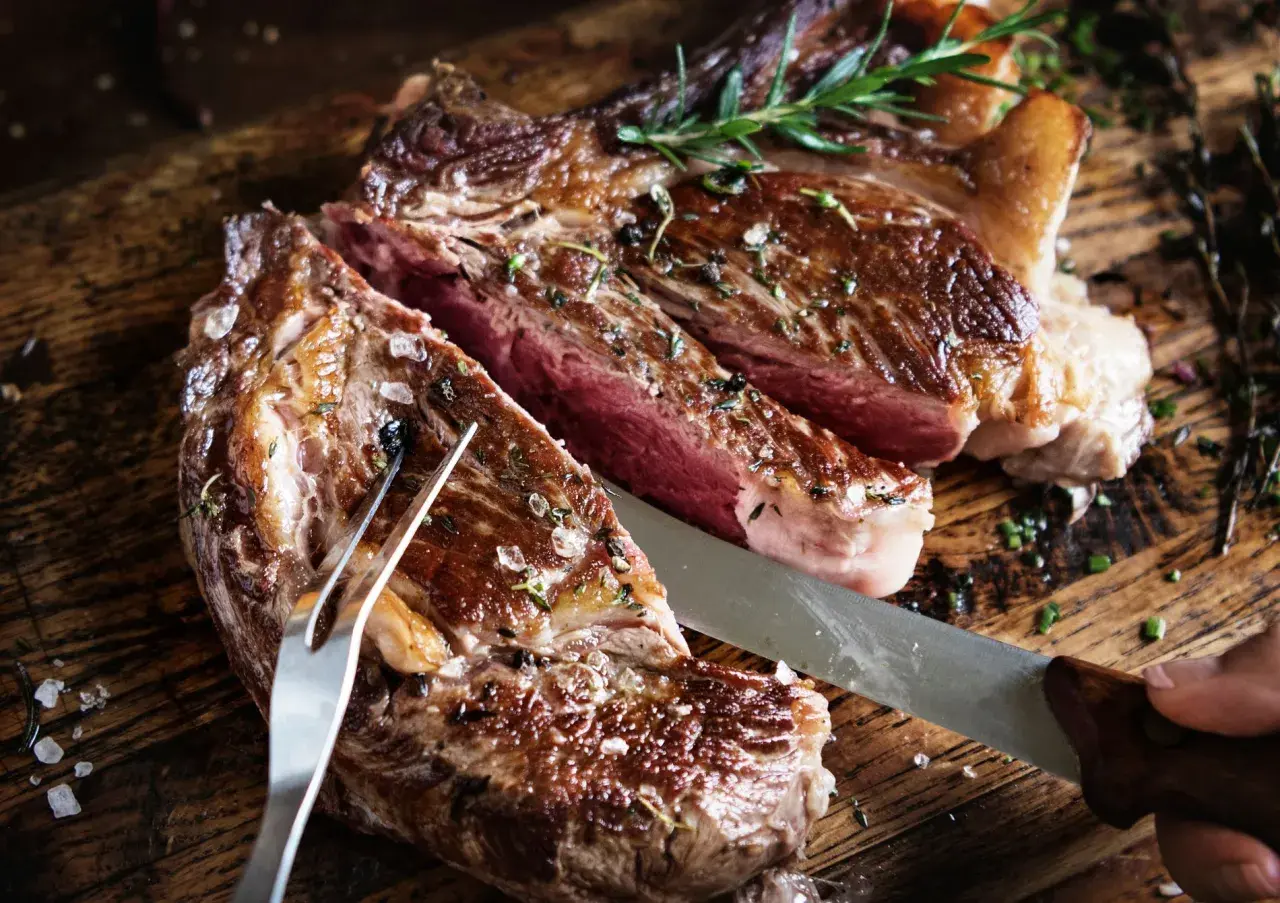 Saftigt bavette steak, perfekt stekt med rosmarin och havssalt, redo att skäras upp på en rustik träskärbräda.