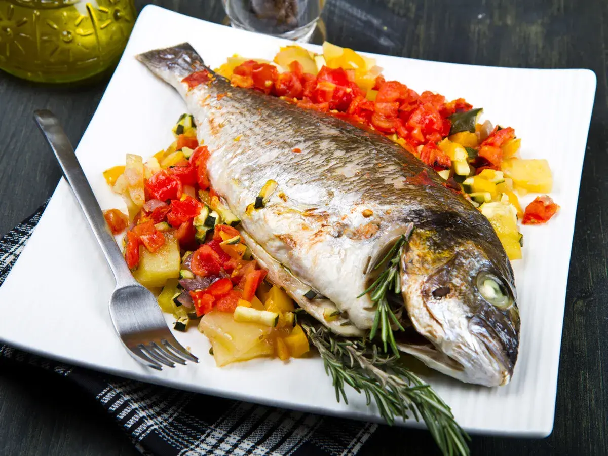 Dorada a la espalda, horneada con verduras y hierbas frescas, lista para disfrutar.