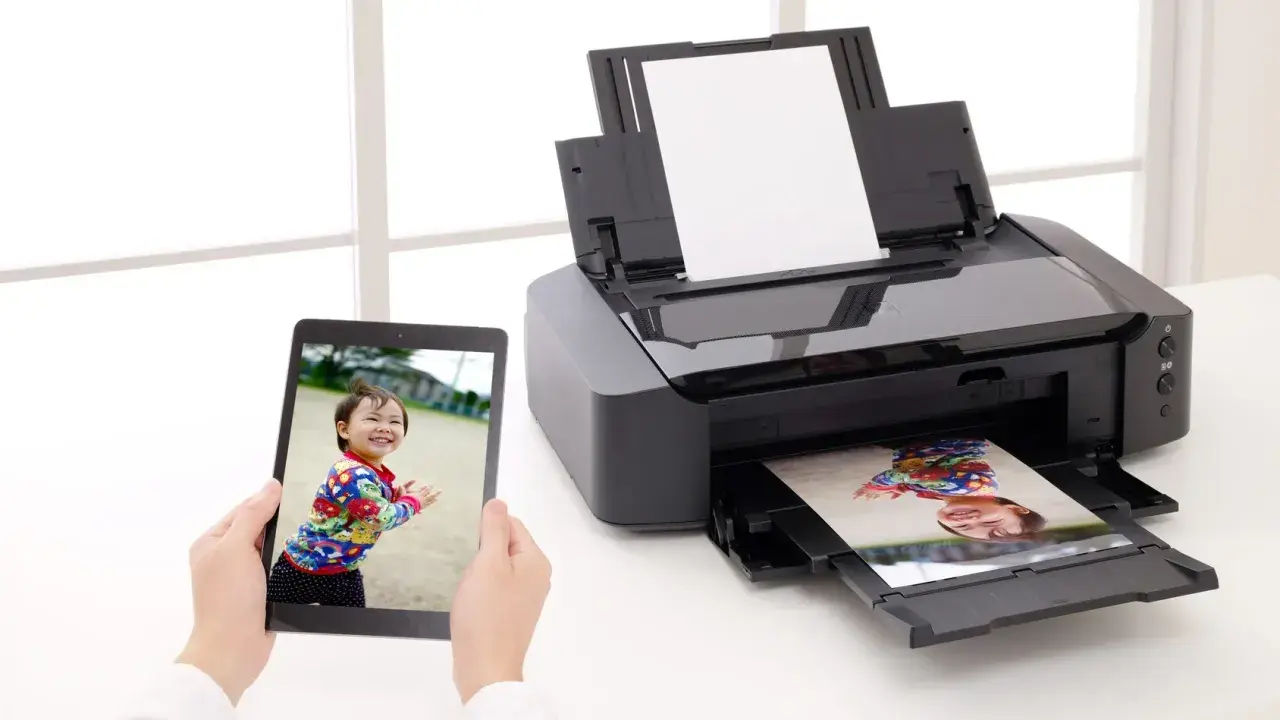 Uchwyć radość dziecka, drukując zdjęcia w domu. Tablet pokazuje uśmiechniętą twarz, a drukarka właśnie wydrukowała podobny kadr.