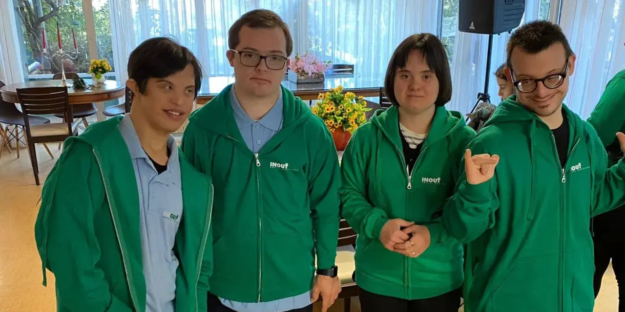 Quattro ragazzi con sindrome di Down, vestiti con felpe verdi, sorridono e posano per una foto.
