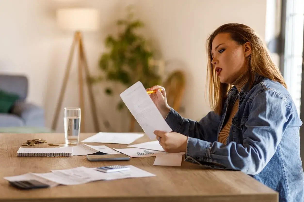 Donna analizza la sua busta paga di 22 giorni lavorativi, circondata da fogli e calcolatrice.