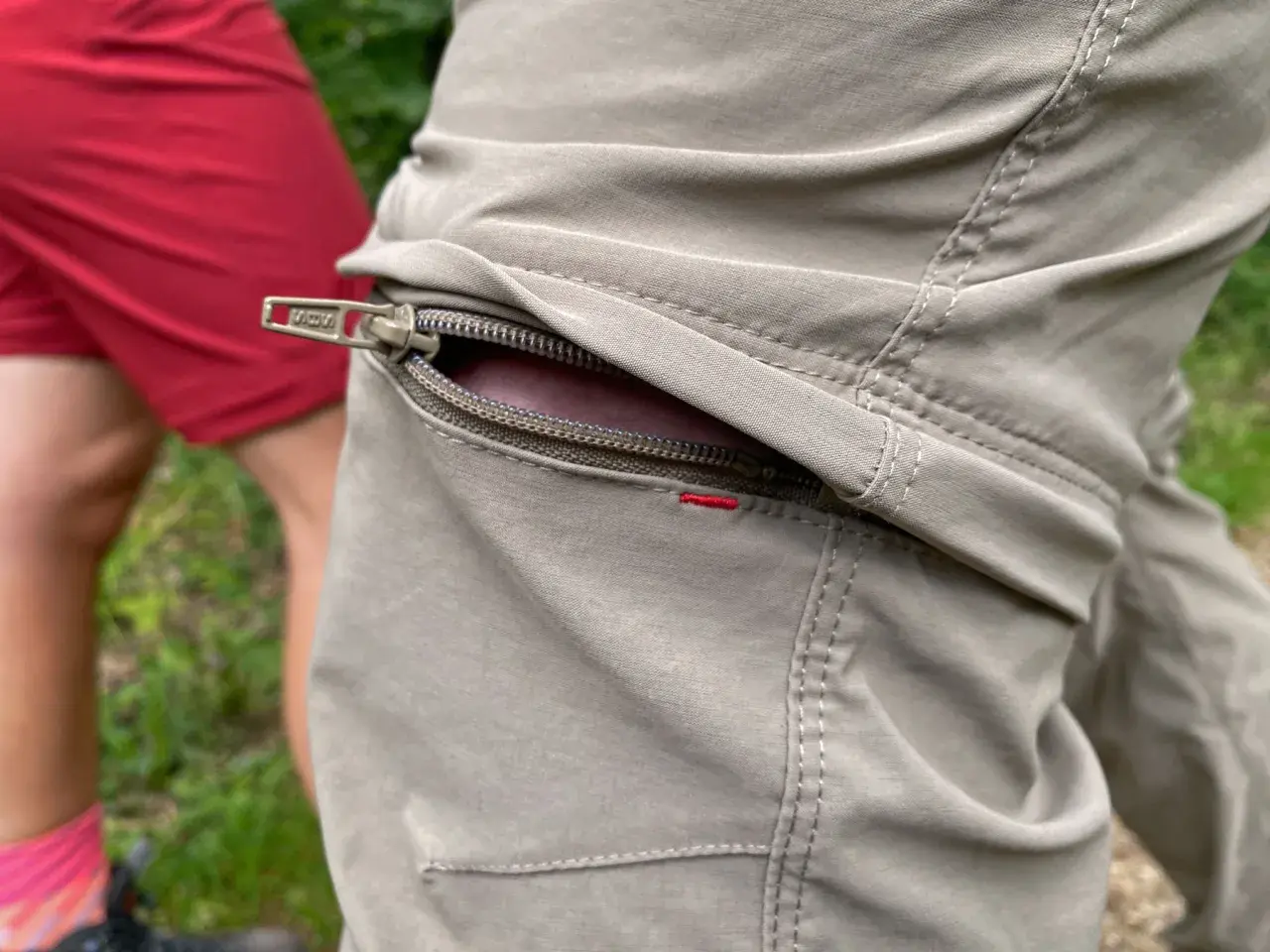 Detailaufnahme einer beige Wanderhose mit Reißverschlusstasche. Perfekt, welche Hose zum Wandern?