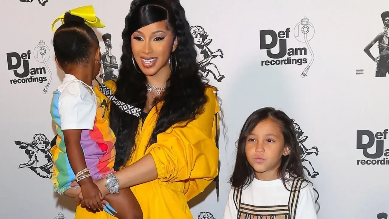 Cardi B z dziećmi na ściance Def Jam. Jedno dziecko w kolorowej stylizacji, drugie obok.