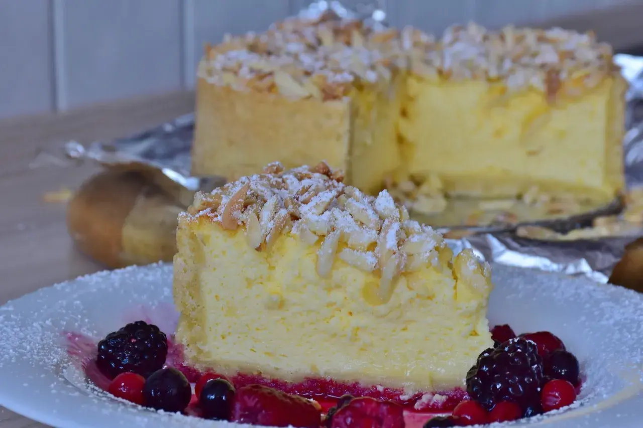 Una fetta di torta di riso ricetta originale, guarnita con mandorle e frutti di bosco, su un piatto bianco.