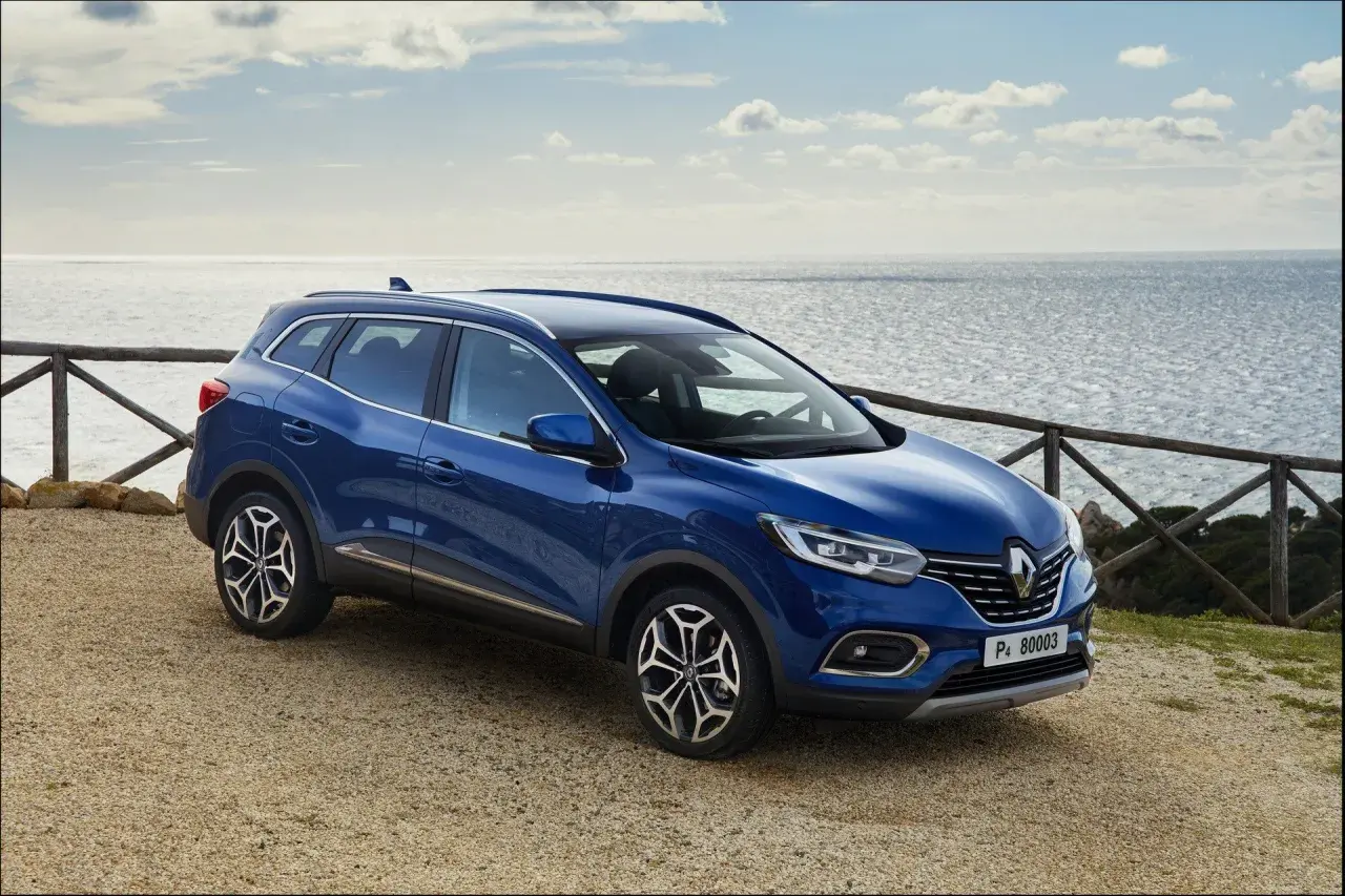 Niebieski Renault Kadjar na tle morza. Wiele pozytywnych **renault kadjar opinie** potwierdza jego wszechstronność.