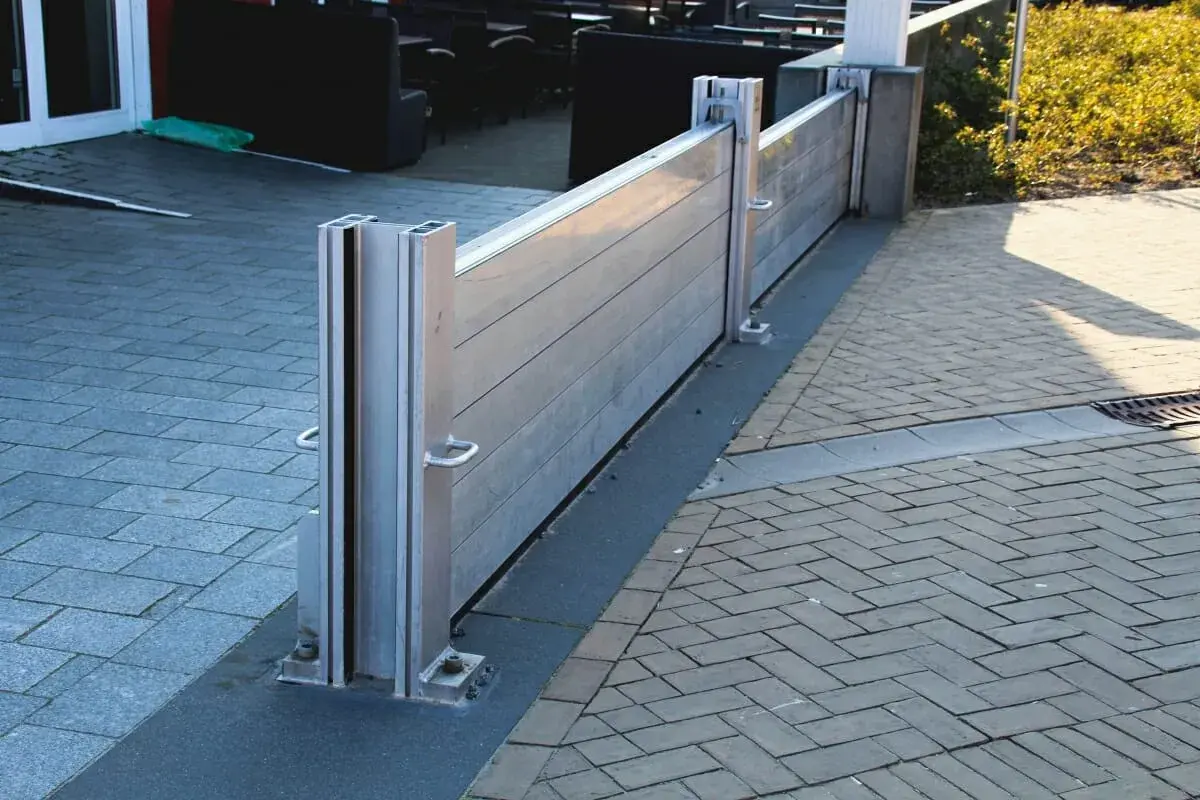 Moderne mobile Hochwasserschutzwand schützt das Haus vor Überschwemmungen. Sie ist aus Aluminium gefertigt und an den Pfosten befestigt.