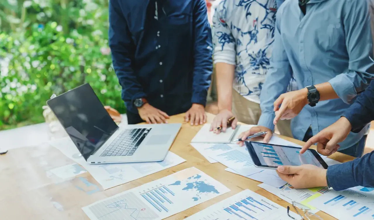 Team discute grafici e dati su un tavolo all'aperto, pianificando i loro buoni propositi per il futuro.