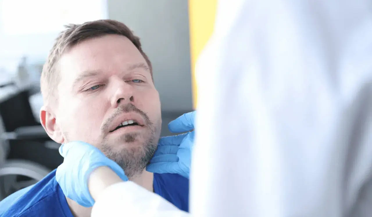 Lekarz bada gardło pacjenta, który skarży się na chrzakanie u dorosłego.