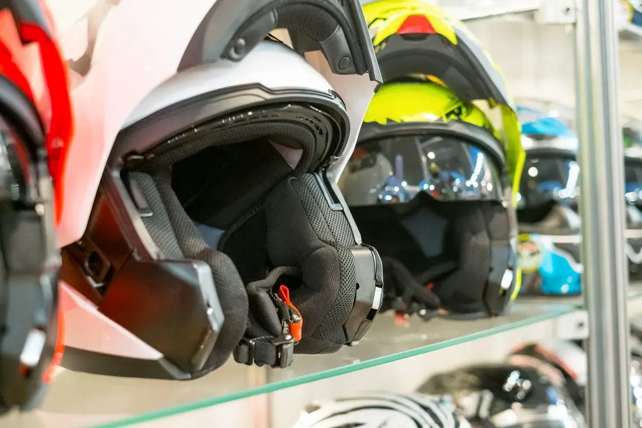 Cascos de moto de varios colores, incluyendo un casco no integral blanco en primer plano, listos para la aventura.