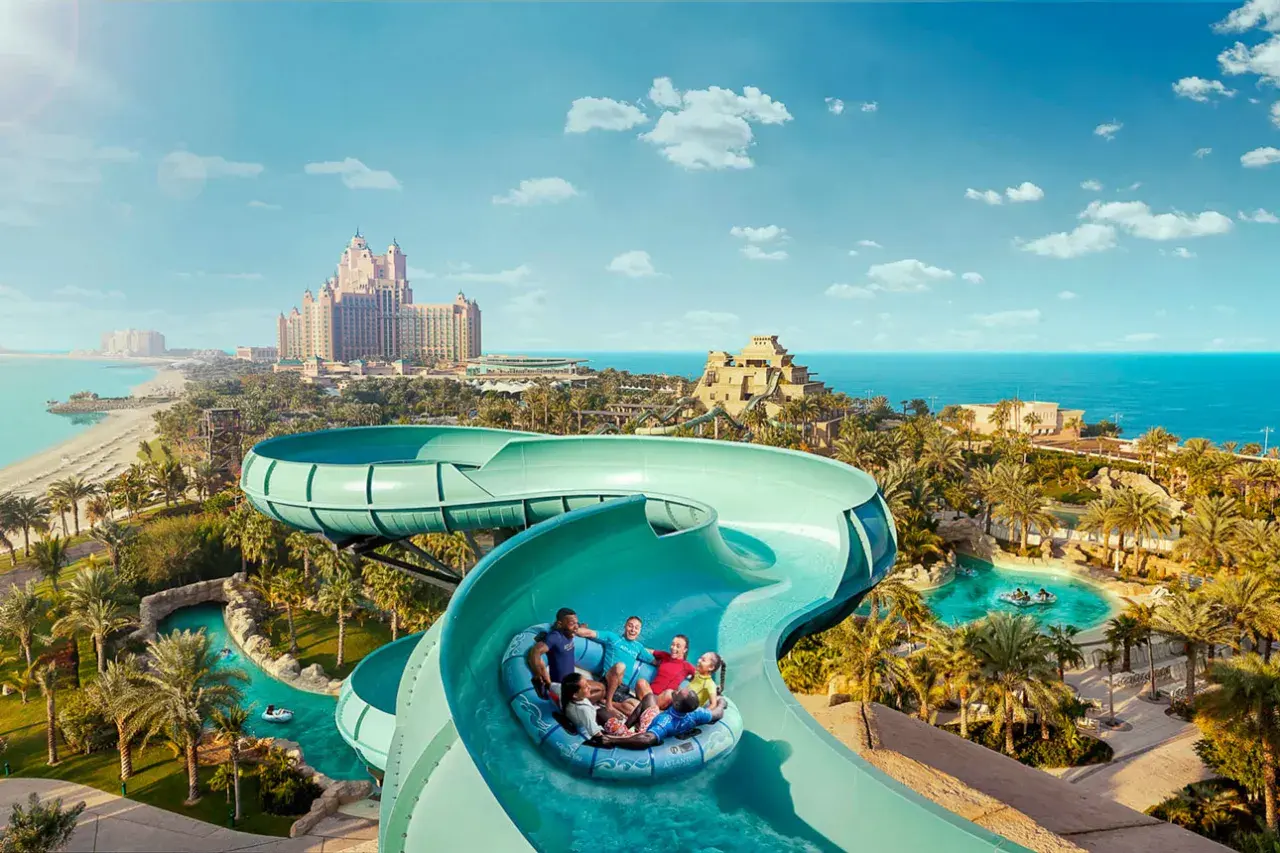 Familie hat Spaß im Dubai Wasserpark auf einer Rutsche, mit dem Atlantis Hotel im Hintergrund.