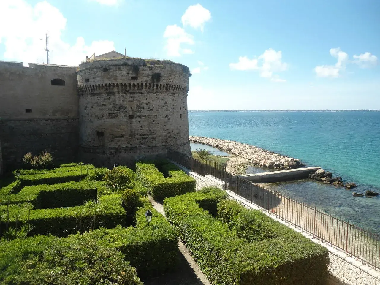 Castello Aragonese e giardini curati, un'idea di cosa vedere a Taranto in mezza giornata, con il mare azzurro sullo sfondo.