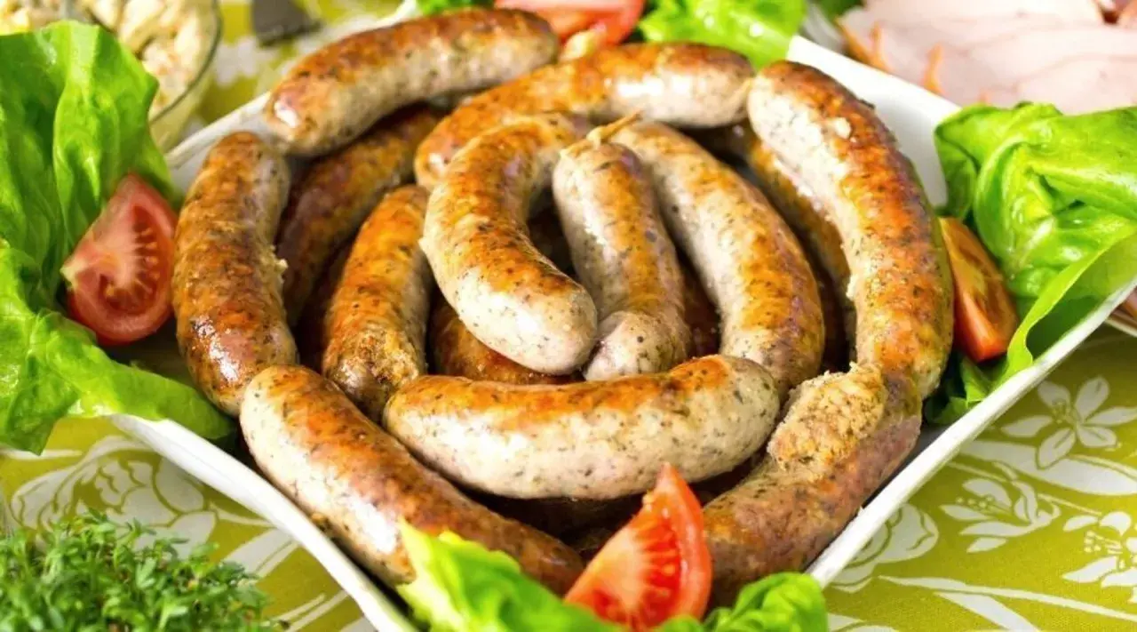 Pyszna biała kiełbasa surowa, idealna do pieczenia. Podana z sałatą i pomidorem.