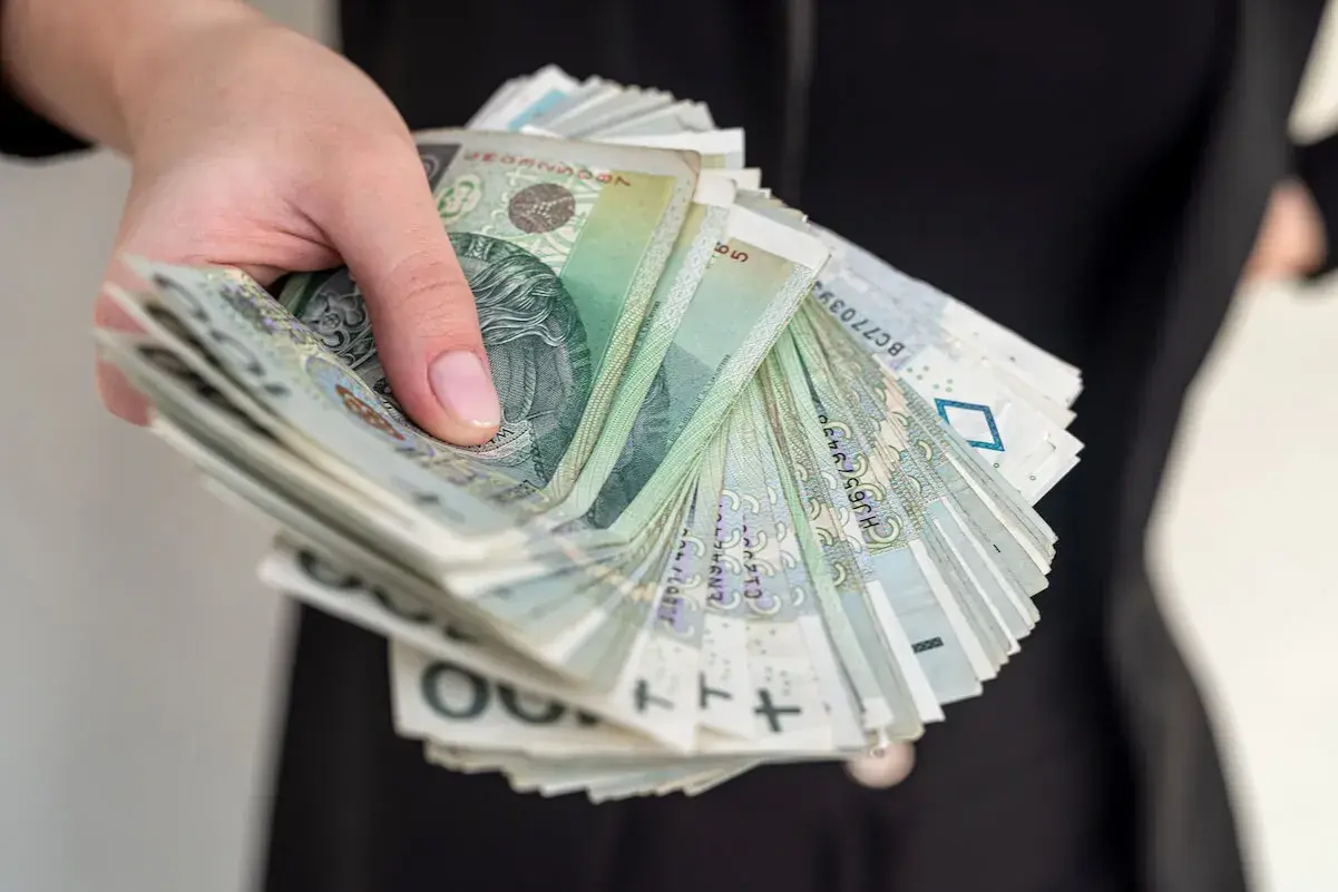 Pieniądze z OFE po śmierci męża. Czy dostanę je do ręki? Stos banknotów w dłoni.