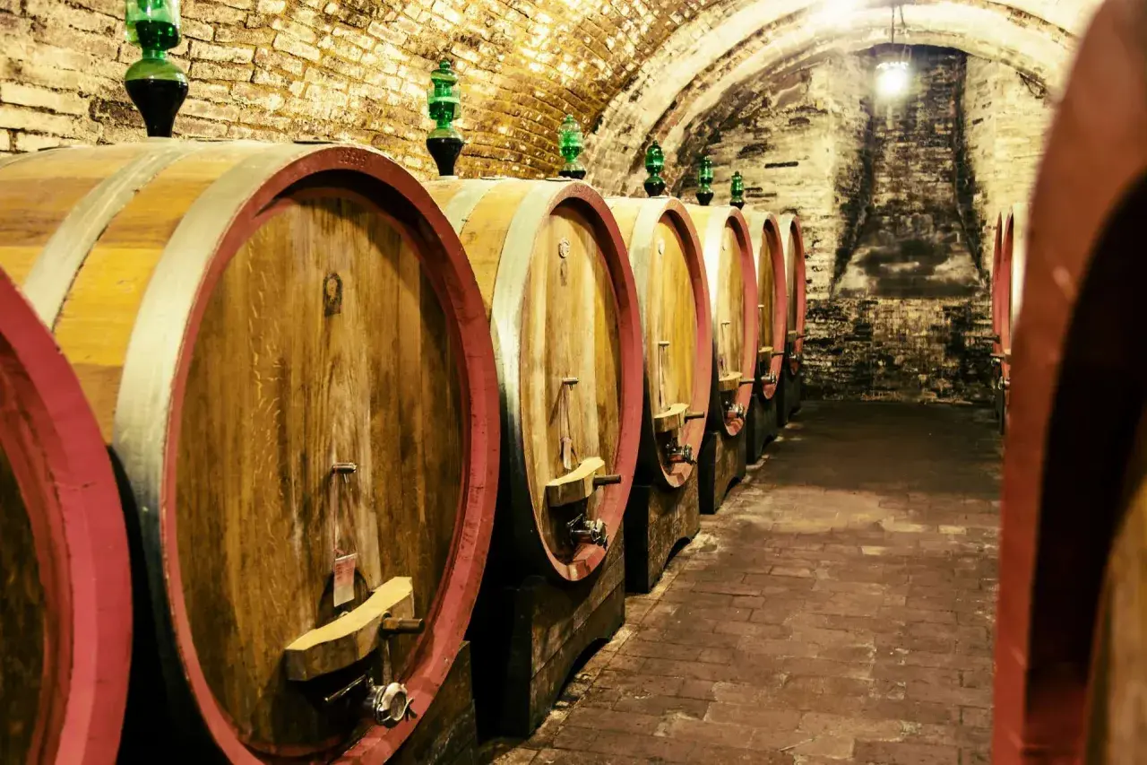 Botti di legno in una cantina storica, un'immagine che evoca le migliori cantine toscane e la loro tradizione vinicola.