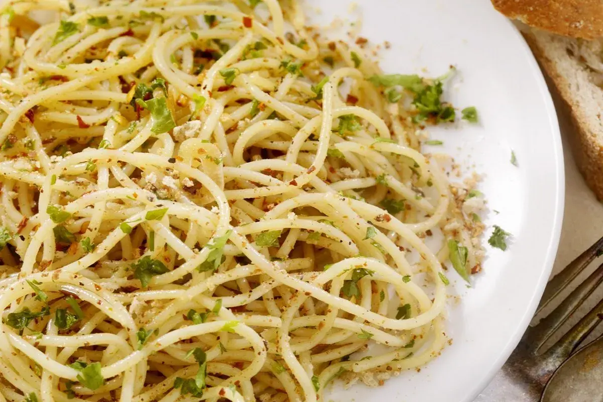 Un piatto di spaghetti alla carrettiera, conditi con aglio, olio, peperoncino e prezzemolo fresco, con una spolverata di pangrattato tostato.