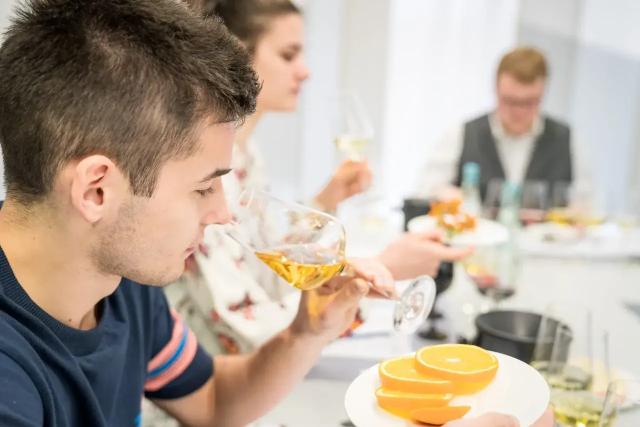 Teilnehmer einer WSET Kurse verkosten Wein und Orangen.