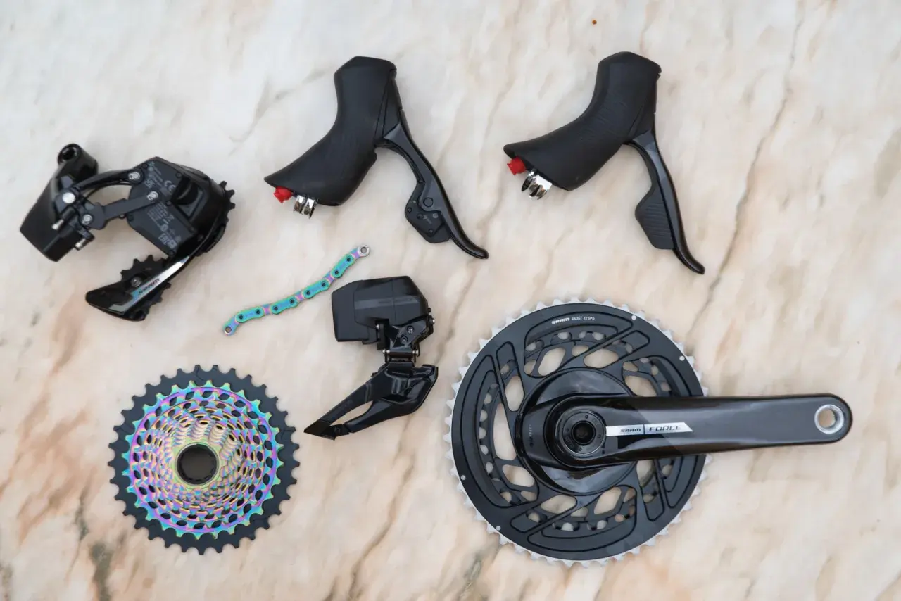 SRAM news: A new Force AXS groupset with rainbow cassette, crankset, derailleurs, and shifters laid out on a marble surface.